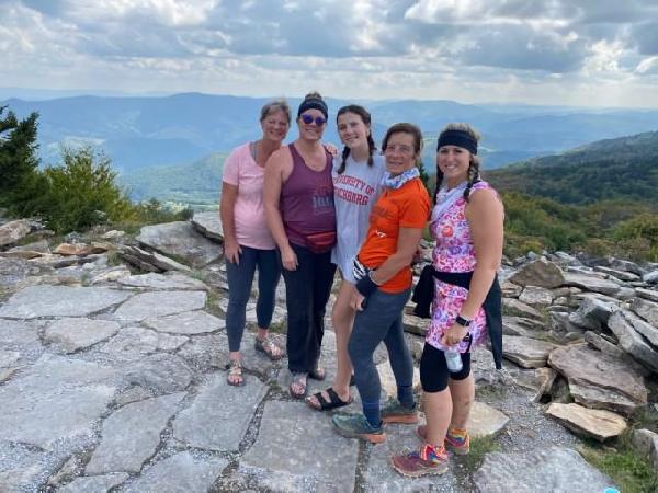 4 female hikers on a rocky top with a mountain view