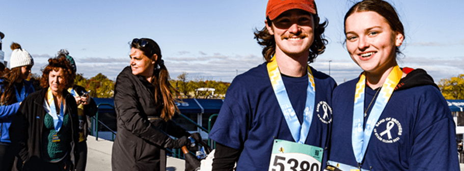 A man and a woman smiling with their race lanyards on.