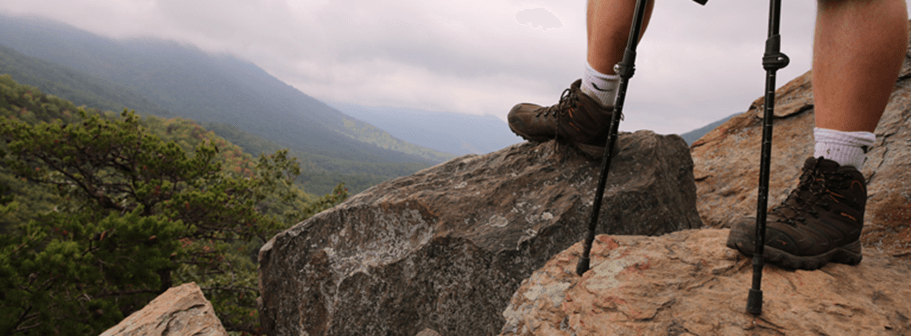 A photo of a HIker's legs standing near a mountain overlook.