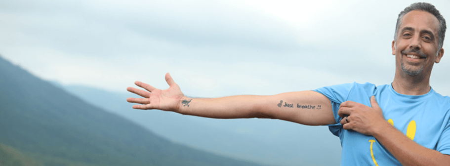A man with a tattoo of just breathe on his arm.